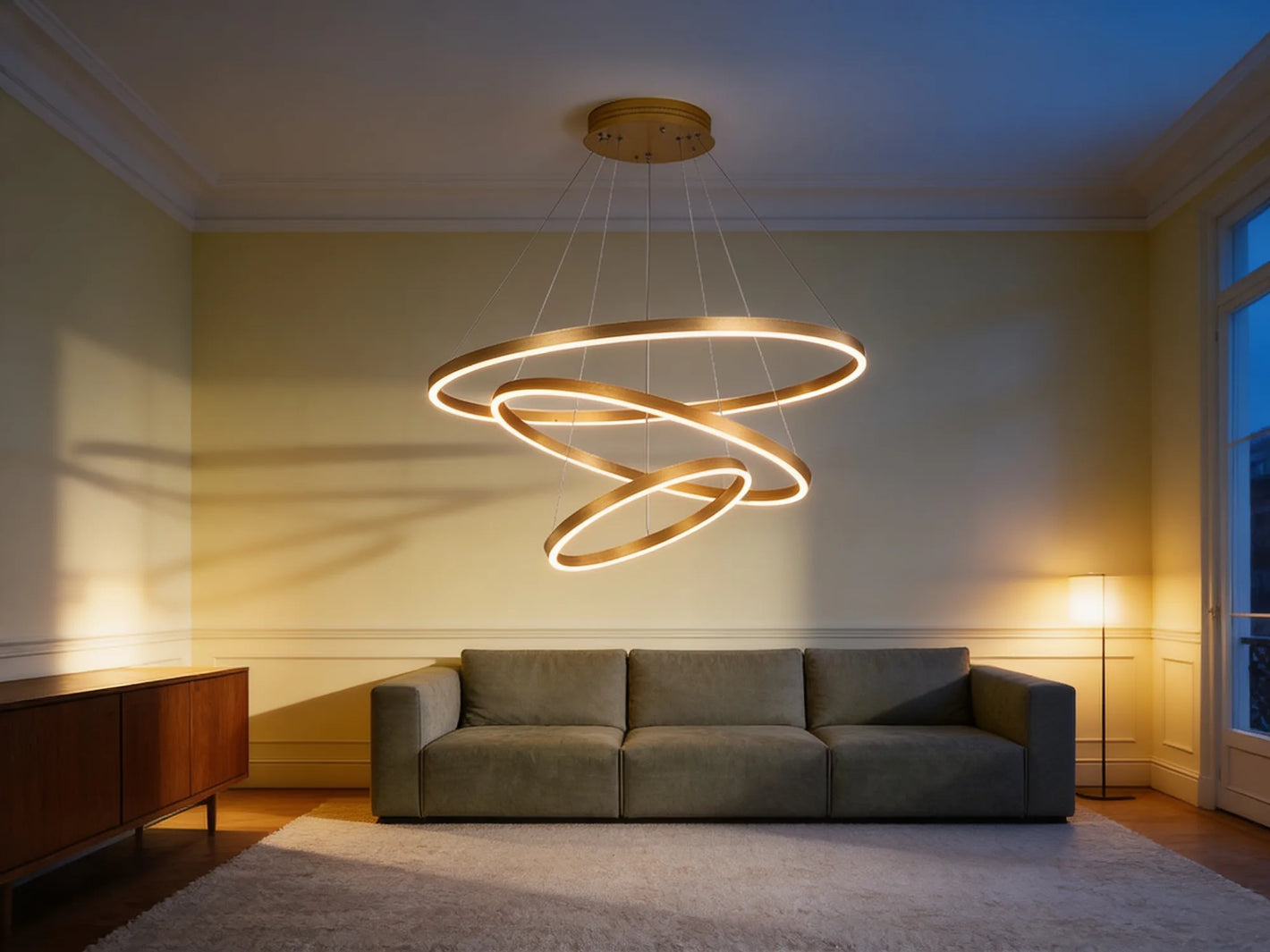 Le lustre allumé au-dessus d'un canapé dans un salon parisien au crépuscule
