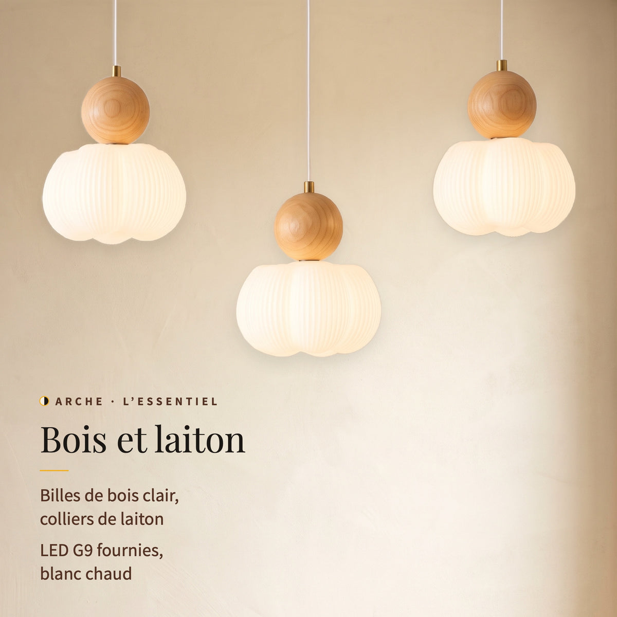 Arche, trois lumières allumées en gros plan : billes de bois clair, colliers de laiton, LED G9 blanc chaud