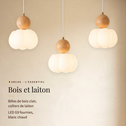 Arche, trois lumières allumées en gros plan : billes de bois clair, colliers de laiton, LED G9 blanc chaud