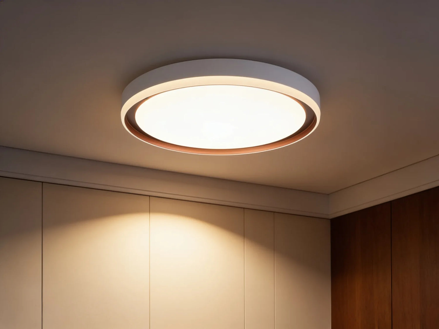 Le plafonnier allume en blanc chaud, nappe de lumiere sur un mur creme