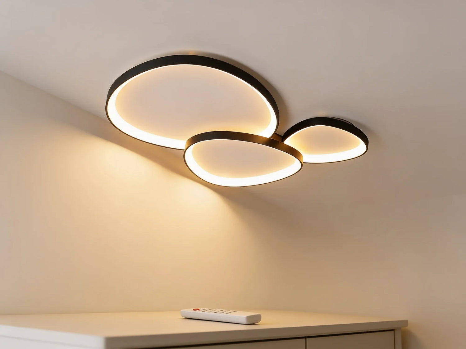 Le plafonnier en blanc chaud, nappe de lumiere sur le mur, telecommande sur une console